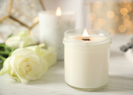 pretty white candle lit with wihite roses around it