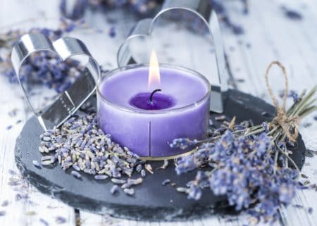 charming lit purple candle with lavender surrounding it