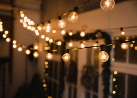 Indoor string lights with Christmas garland hanging on door in background