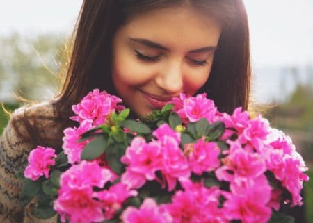 Young cute woman smelling pink flowers