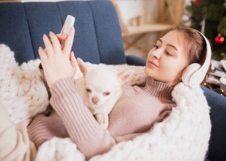 Young woman in blanket on couch listening to musich warm and cozy atmosphere