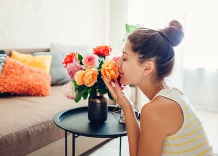 woman smelling beautiful bouquet of yellow and red and orange flowers